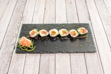 Yağlı maki rulo suşi ile Norveç yosunu, kırmızı ton balığı, zencefil, susam tohumu, krem peynir, soya sosu, çıtır soğan, avokado ve taze soğan.
