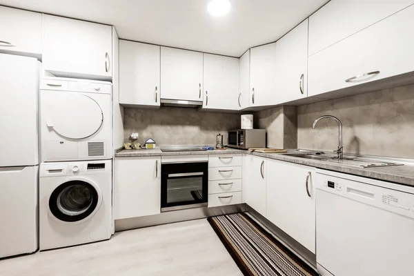 大厨房 配有家用电器 立柱洗衣机和烘干机 灰色台面和带有轻型木地板的白色橱柜 — 图库照片