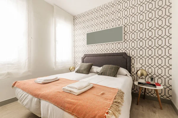 Çift kişilik yatak odası, beyaz yastıklar, kahverengi yastıklar ve kısa süreli kiralık bir dairede battaniyenin üzerinde katlanmış havlular.