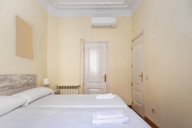 İki yataklı yatak odası, beyaz yatak başlığı, ahşap yatak başlığı ve beyaz marangozluk.