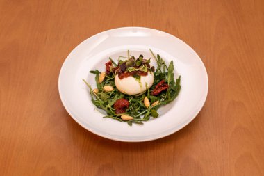 Tipik İtalyan Burrata salatası roka, zeytinyağlı kurutulmuş domates, pesto sosu ve soyulmuş badem.