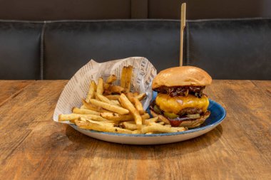 Eritilmiş çedar peynirli iki etli biftek, soğan, turşu, pastırma ve bol patates kızartması.