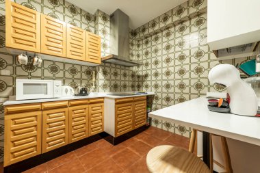 Beyaz taş tezgahlı mutfak, sağlam ahşap dolaplar ve duvarlarında antika fayanslar.