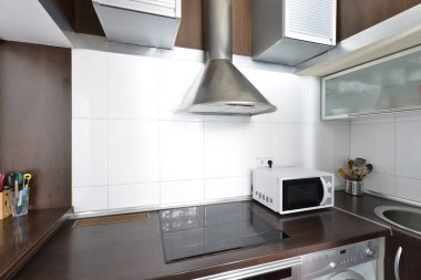 Koyu ahşap dolaplı mutfak ve gri aletlerle uyumlu tezgah.