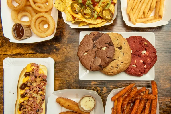 Set of fast food dishes with french fries, sweet potato chips,chocolate cookies, nachos with guacamole, onion rings, fried yucca and fried chicken in batter