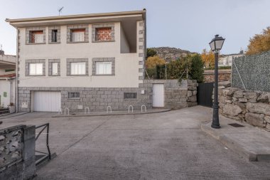 Çimento sokakları ve demir sokak lambaları olan tek bir aile evinin dış alanı.