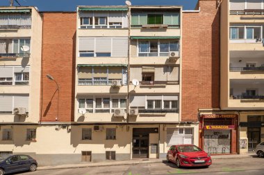 Kapalı terasları ve zemin kattaki ticari binaları olan apartmanların ön cephesi.