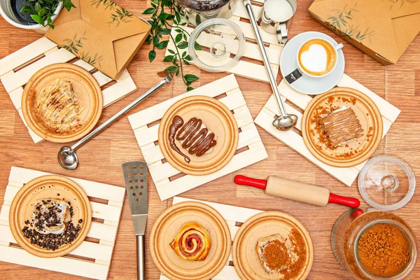 Set of wooden plates with condiments and utensils for cooking cinnamon roll with chocolate, a lot of cinnamon, chocolate chips, ham and cheese