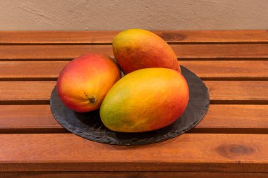 Yuvarlak siyah tepside taze mangolu tepsi.