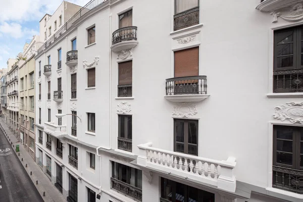 White painted vintage building facade in a narrow street in the center of Madrid