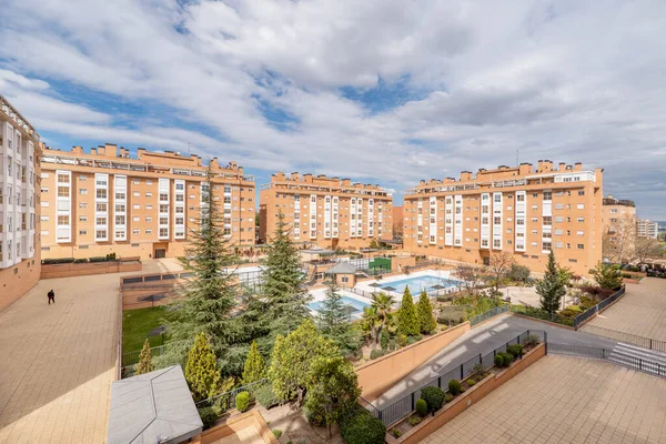 Common areas with swimming pools and gardens in a development of urban residential buildings on a cloudy and clear day