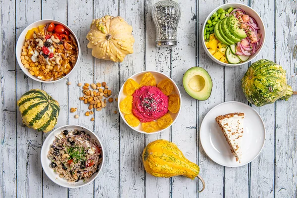 Set of healthy food dishes with avocado, red onion, cooked quinoa, Spanish olives, dried fruit with berries, pumpkin and sesame seeds