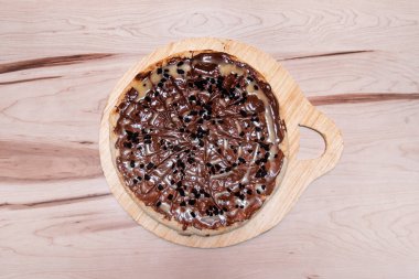 İspanyol nocillasıyla tatlı pizza, ahşap masada çikolatalı kurabiye.