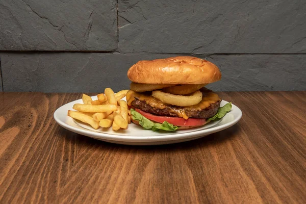 Delicious beef burger with melted cheese, onion rings and french fries