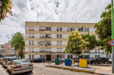 Facade of cheap houses with urban waste collection system on the street on a cloudy day