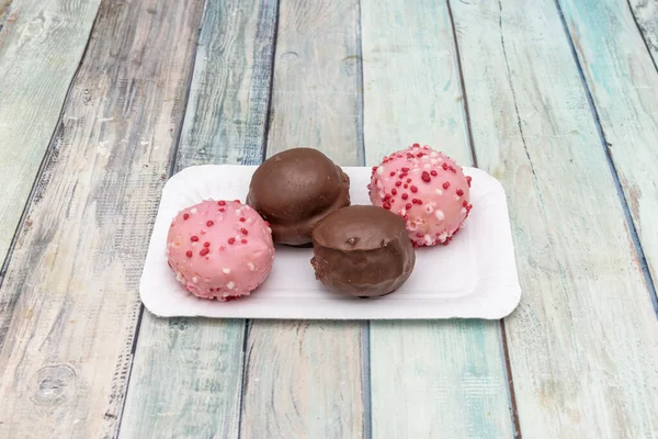 Dark chocolate and pink chocolate balls with coconut fillings on wooden table