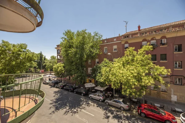 Çevresinde ağaçlar, bahçeler ve metal parmaklıklı yarı dairesel balkonlar olan konut binalarının cepheleri.