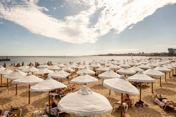 Crowd of white fabric umbrellas protecting bathers on Estoril beach
