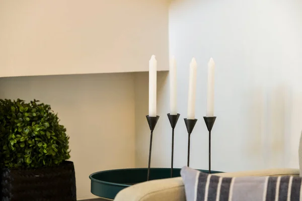 Corner of a room with black candle holders with white candles on a green circular tray