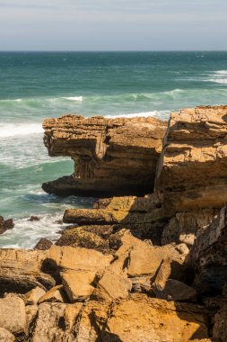 view of the sea from a cliff lashed by waves on a summer day