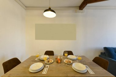 Kahverengi kadife kaplamalı dikdörtgen ahşap yemek masası, meyveli cam kase ve bisküvili ördek ve tatlı.