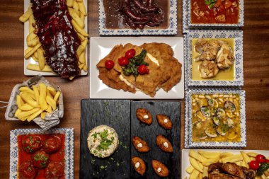 Tabaklar ve tepsiler dolusu İspanyol gastronomisi kroket tapas, köfte, midyeli fasulye, sarımsaklı tavuk, şarap sosisi ve Rus salatası.