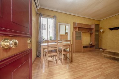 Ahşap mobilyaları ve ahşap döşemeleri olan sokak kapısına doğrudan erişimi olan bir evin oturma odası.