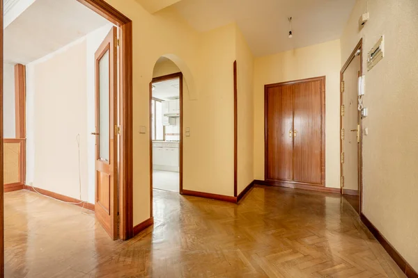 Entrance hall of a house with cherry wood door, herringbone oak parquet flooring, access to multiple rooms, fitted wardrobes and cream yellow painted walls