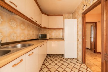 Eski mobilyalarla döşenmiş mutfak, mikrodalga fırını olan ahşap tezgah duvarlarda ve zeminlerde antika fayanslar.