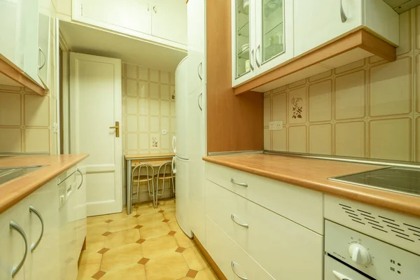 kitchen with light cabinets, matching appliances and wooden countertops in an apartment with striking tile floors