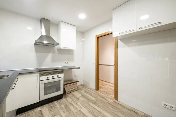 黒石カウンター 光沢のある白いキャビネット 木製の床やステンレス製の家電付きの新しくインストールされたキッチン — ストック写真