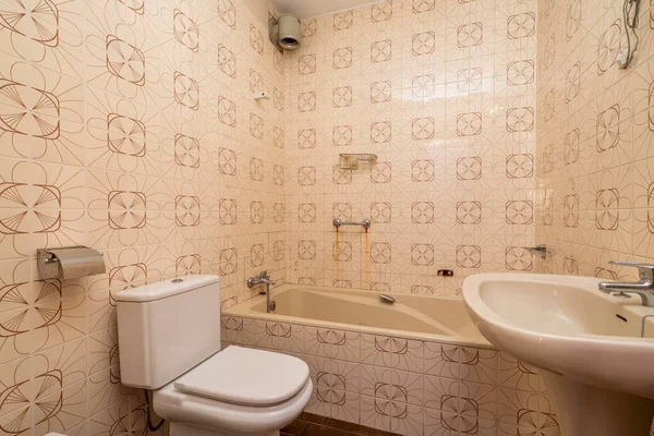Bathroom with bathtub and white porcelain toilets and vintage tiles with brown details