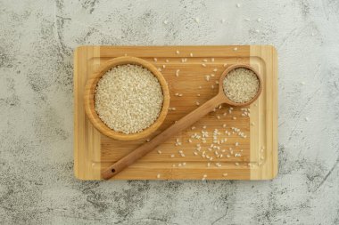 Tahıllı pirinç, bambu ahşap bir kâse, tahta bir kaşık ve bambu bir tahtanın üzerinde.