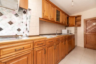 Bir duvar boyunca kırsal klasik ahşap mobilyalı mutfak.