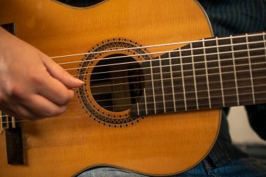 Uzun tırnaklı bir müzisyenin eli sekiz telli bir perdeyi çalıyor.