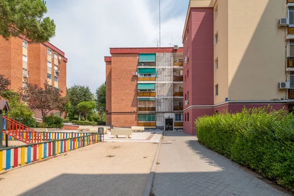 Facades of urban residential buildings with gardens in common areas with playground and white stone benches