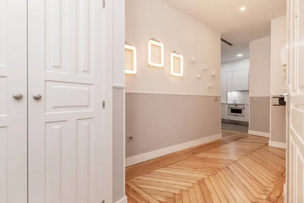 Hallway of a vacation rental house with a built-in closet with white wooden doors and beautiful pine wood flooring