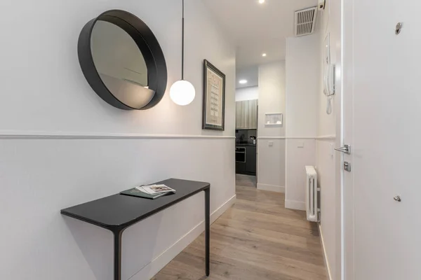 Hallway of a vacation rental home with black designer sideboard and matching circular mirror