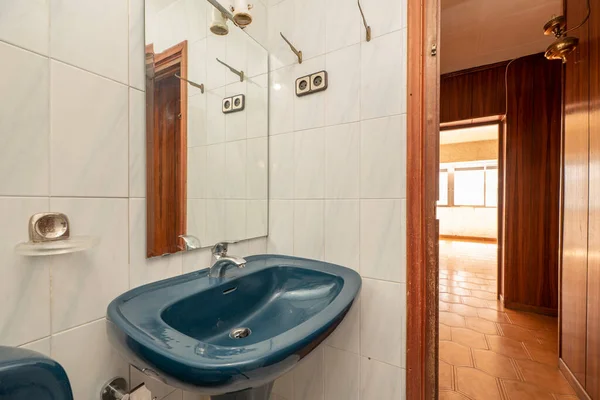 Blue porcelain pedestal sink with matching frameless mirror in small bathroom