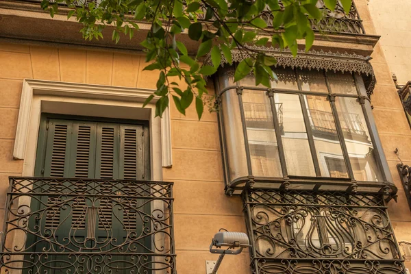 ガラス窓付きの古いレンガ造りの建物の上に古典的なレトロな錬鉄製の古い金属製のバルコニー付きの古い家の植物と黄色のファサード — ストック写真
