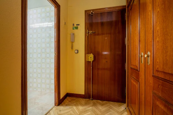 Entrance hall of an urban residential home with oak parquet flooring, mahogany cabinets and doors, and yellow painted walls