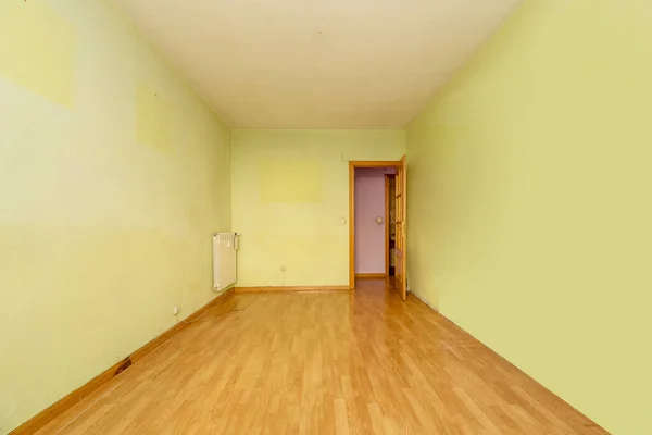 Empty room in an old flat built with modest qualities, pistachio green painted walls and wooden floors