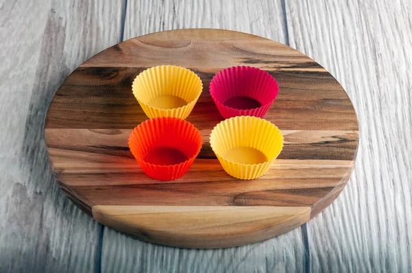 Dört renkli silikon kalıp tahta bir standın üzerinde duruyor ve gri bir arka plan.