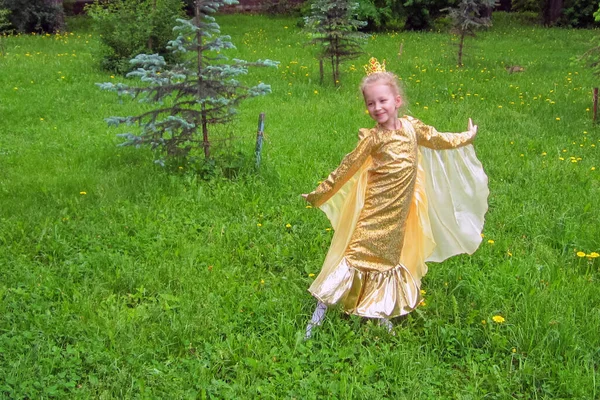 Kırmızı balık elbiseli küçük bir kız yeşil bir parkta poz veriyor. Yaz. Gün.