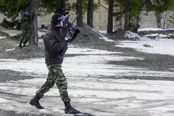 Silahlı üç genç adam paintball oynuyor. Olağanüstü bir spor. Aktif dinlenme, boş zaman..
