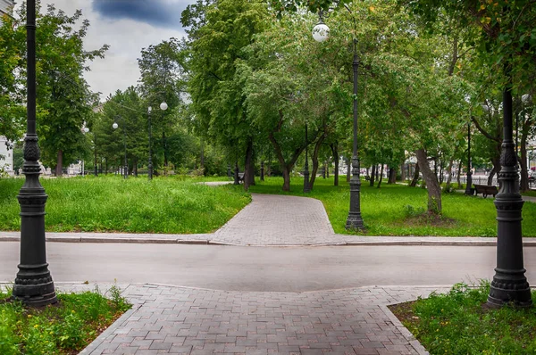 Şehir parkında sokak lambaları olan yeşil bir sokak. Yaz günü.