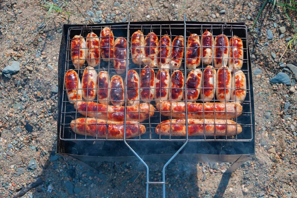 Lezzetli sosisler ızgarada kızartılır. Güneşli bir yaz günü. Piknik