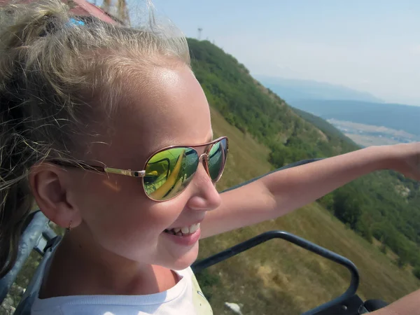 Aynalı gözlüklü bir kız teleferiğe atlıyor..