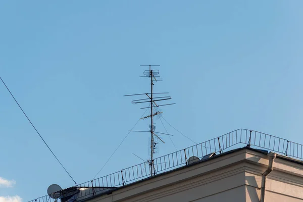 Evin çatısında, mavi gökyüzüne karşı televizyon anteni.