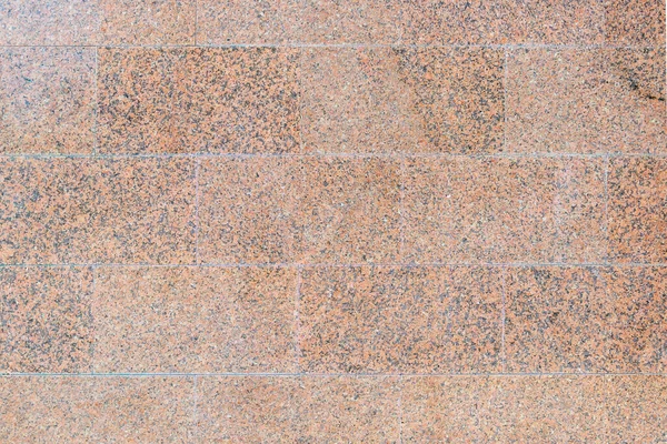 Yumuşak cilalanmış taştan yapılmış kahverengi granit duvar. Blokların Masonluğu. 